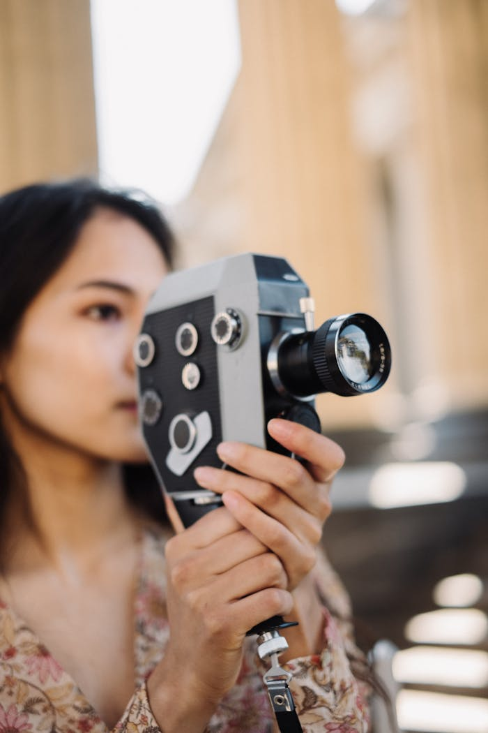 Services Woman holding a vintage film camera, capturing an artistic scene outdoors.